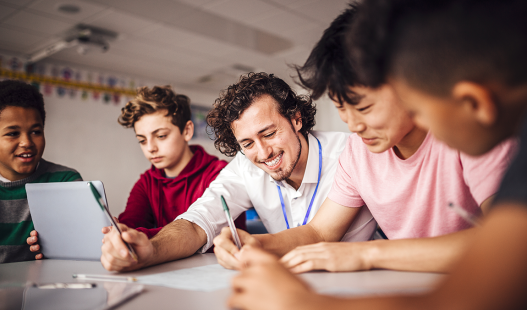 Four students working at a table with their teacher
