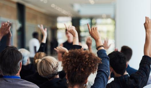 A group of people in a room raising their hands to vote
