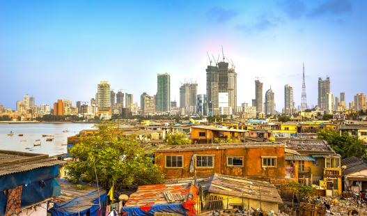 Photograph of Mumbai City, India, showing new construction of skyscrapers in the background and makeshift homes in the foreground.