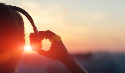 person wearing headphones and holding one side of them away from their ear